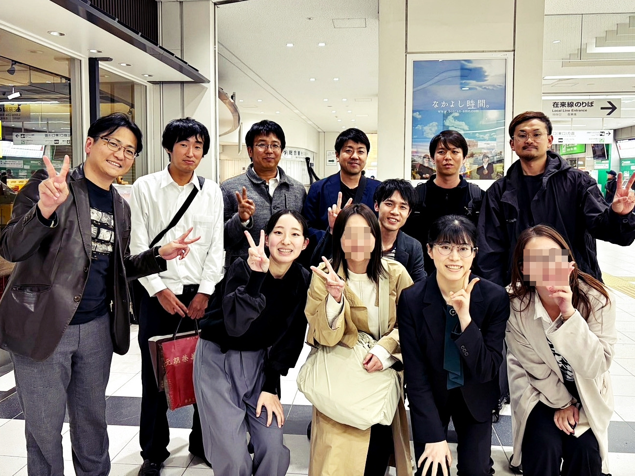 初日。鹿児島中央駅にて記念撮影!笑顔の参加メンバー10名(ひとりで2列目を占めるのが中村社員)