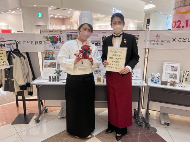 コックコートを着用し、食育の取り組みとしてお子様向けのミニゲームを案内した木下(左)